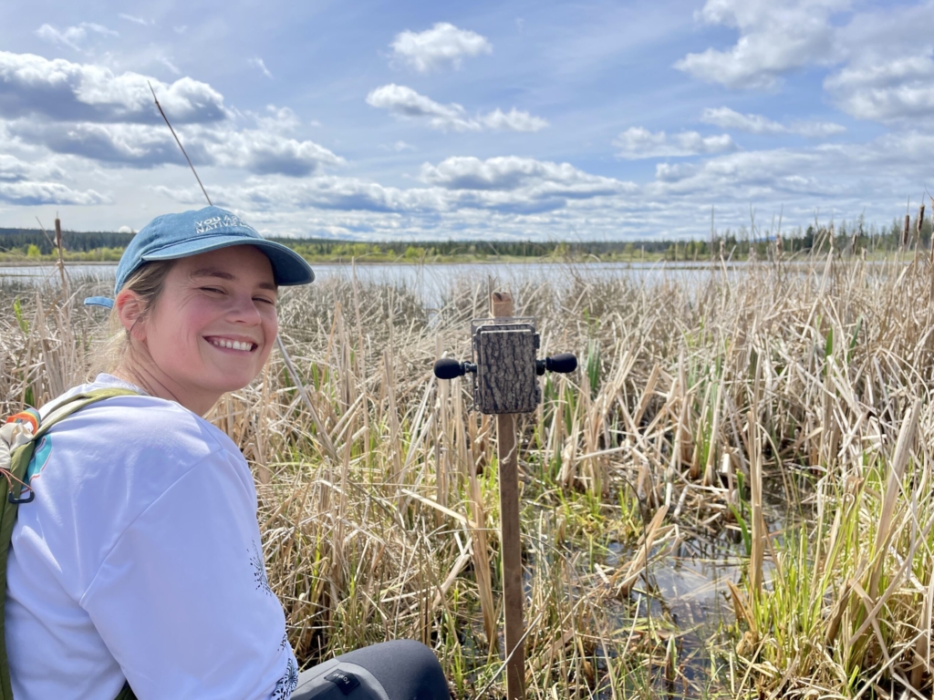 A field staff smiles next to a deployed ARU.