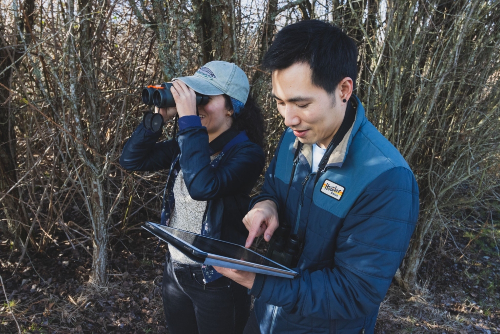 Two people volunteering, one has an iPad and the other has binoculars