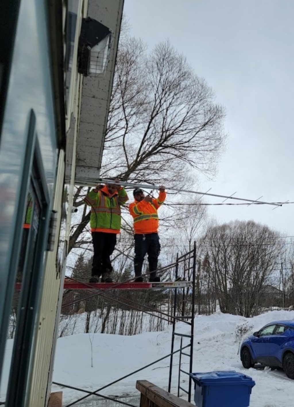 Two people install a Motus tower on a building.