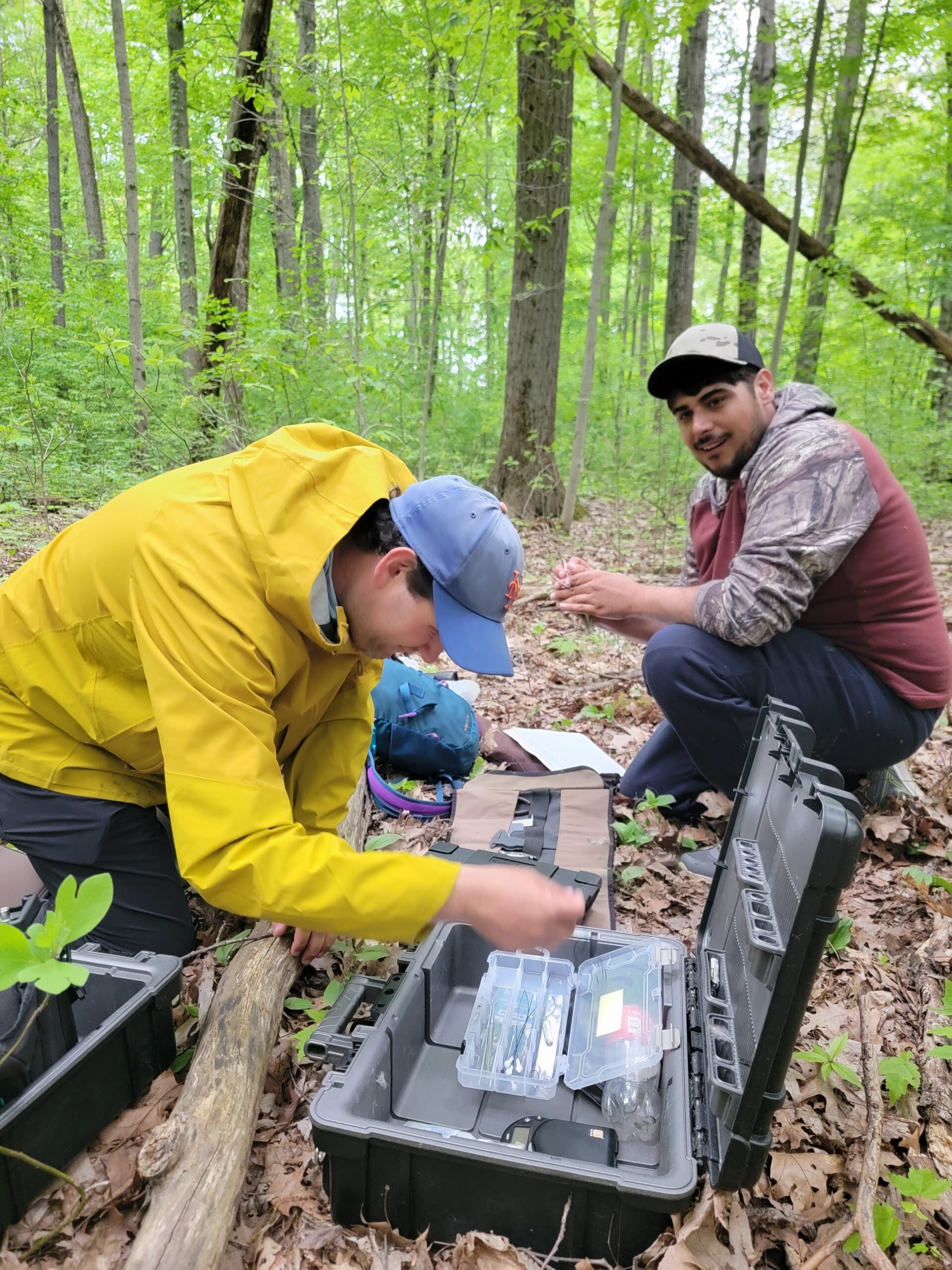 Two participants of a Motus workshop look through gear in the forest.