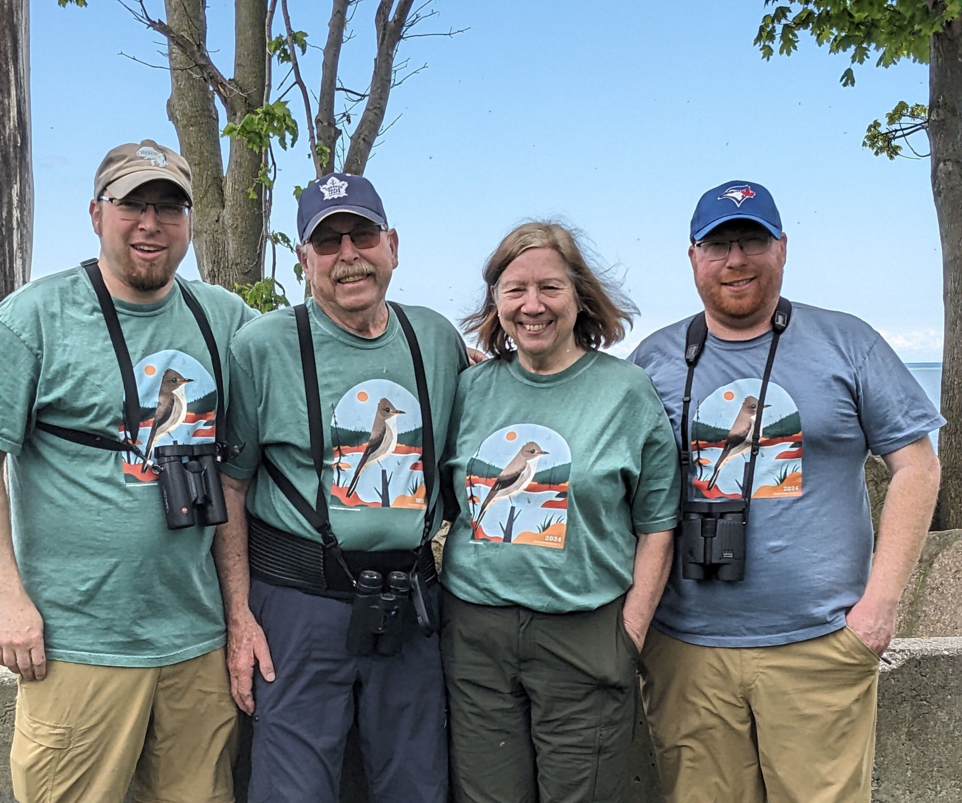 Quatre participants du Birdathon portant le même t-shirt et équipés de jumelles