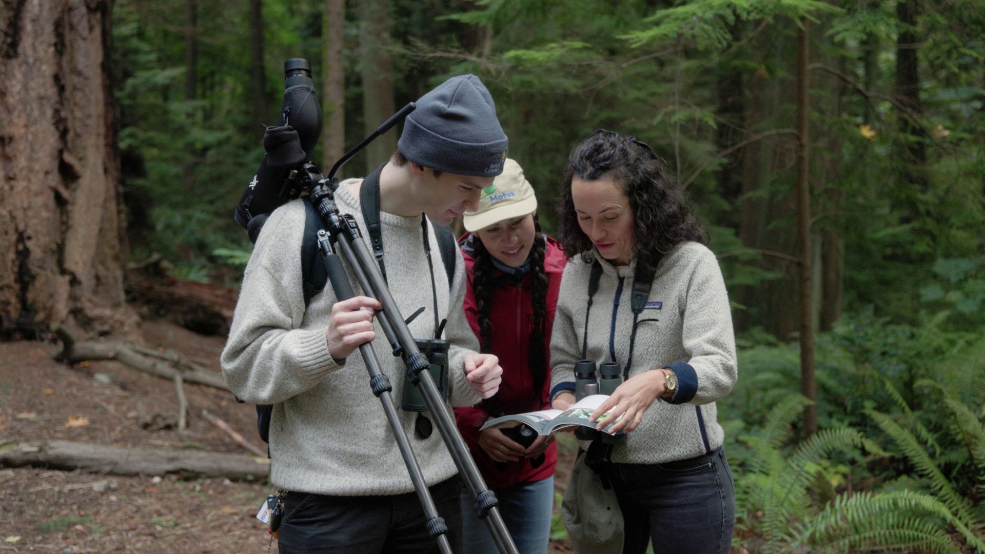 Three people gather around a birding field guide
