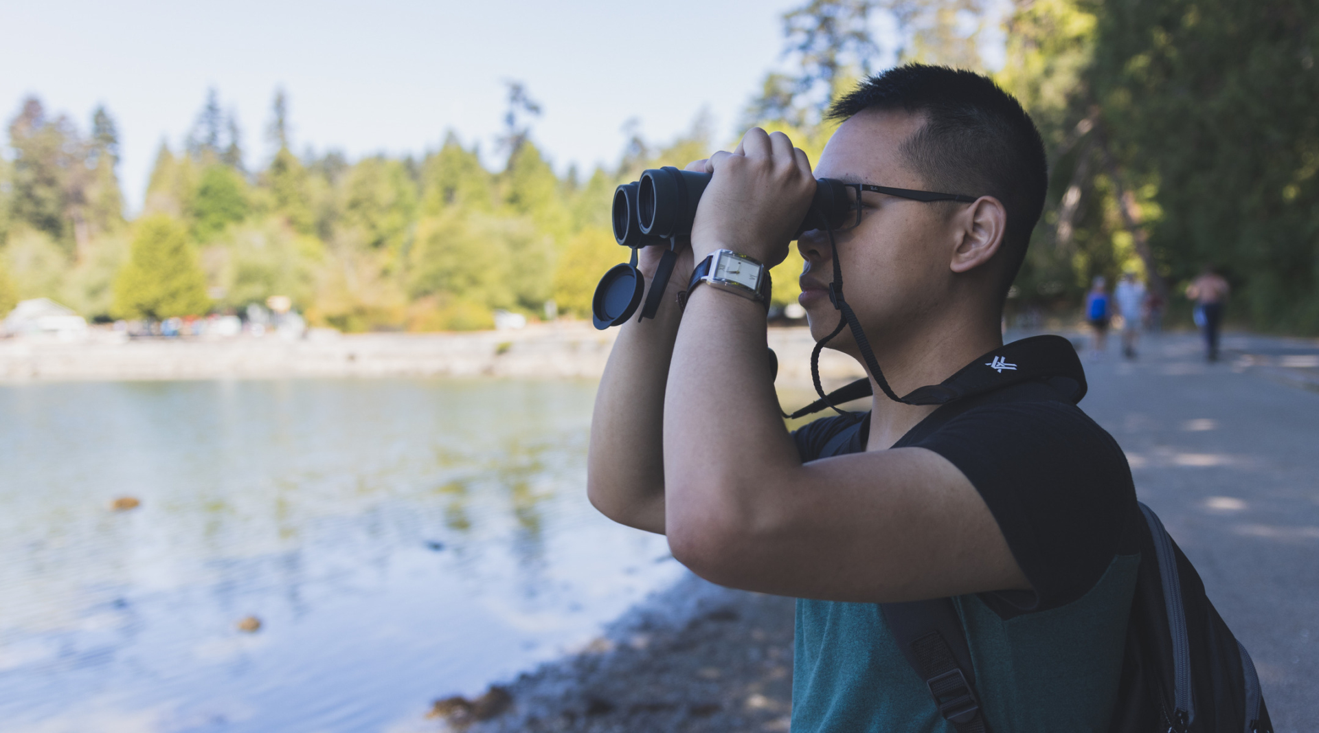 A person holds a pair of binoculars up to their face.