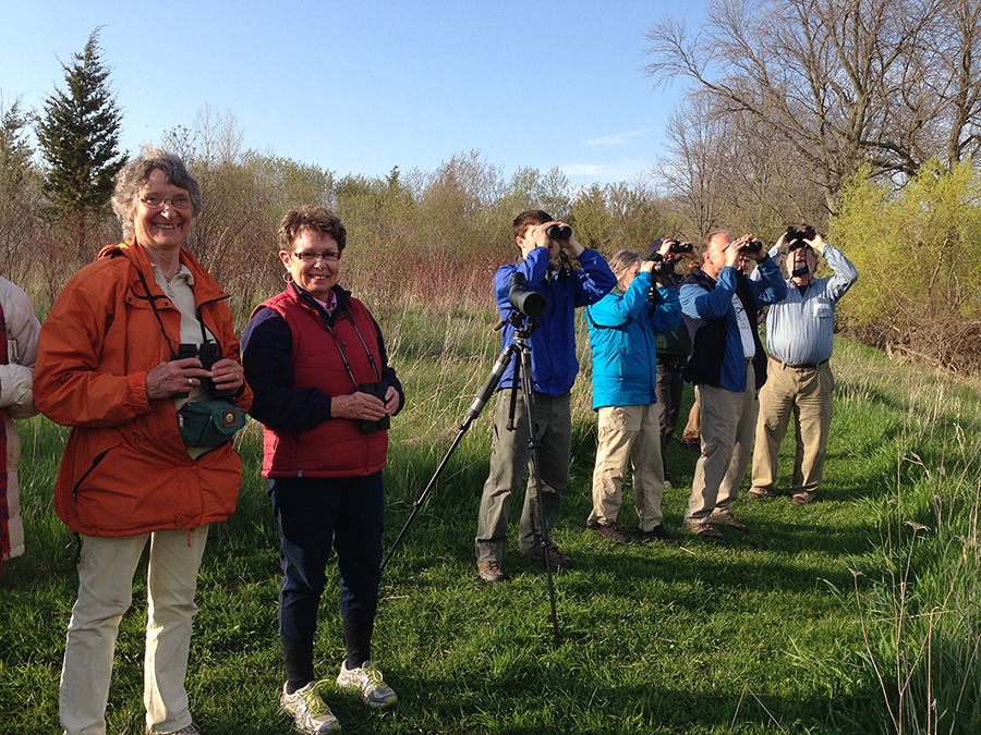 A group of birdathoners smiling and looking for birds in the forest