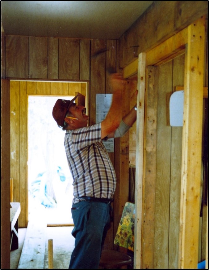Doug Tarry martèle une poutre suspendue lors de la construction de la cabane Tip Point en 1987.